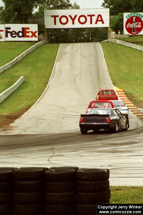 Mark Pluer's Ford Thunderbird trails a pack of cars headed uphill to turn 6.