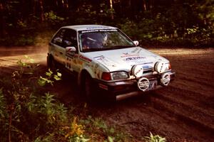 Lauchlin O'Sullivan / John Dillon Mazda 323GTX at a 90-right on SS1, Akeley Cutoff.