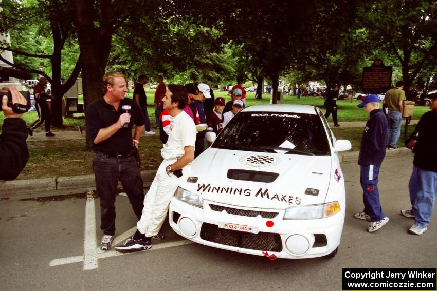 Érik Comas is interviewed by Doug Plumer in front of the Mitsubishi Lancer Evo IV he and Julian Masters shared.