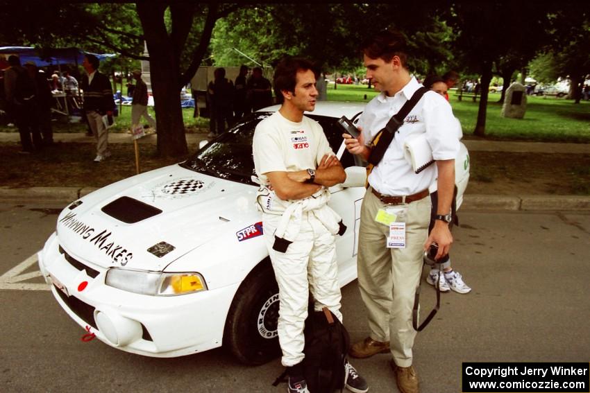 Érik Comas is interviewed by Jeff Burmeister in front of the Mitsubishi Lancer Evo IV he and Julian Masters shared.