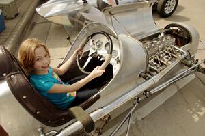 A spectator fits into an old midget racer on display.