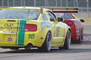 Rob Bodle's Ford Mustang gets passed by Doug Peterson's and Amy Ruman's Chevy Corvettes at turn 4.