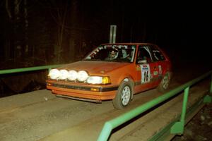 Gail Truess / Pattie Hughes Mazda 323GTX at speed across the final bridge on SS10, Menge Creek.