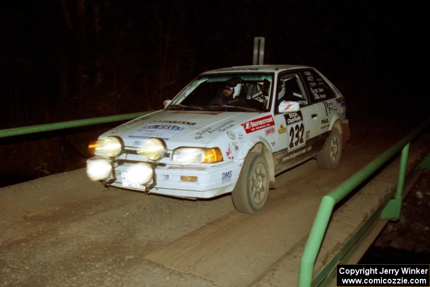 Mark Tabor / Kevin Poirier Mazda 323GTX at speed across the final bridge on SS10, Menge Creek.