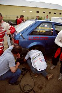 The Darek Bosek / Piotr Modrzejewski Mazda 323GTX receives repairs at service after driving with a flat on a stage.