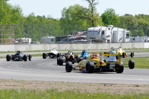 Formula cars stream through the carousel on the pace lap.