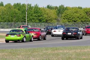 The field of Spec Miatas all bunched together at turn 4 on the first lap.