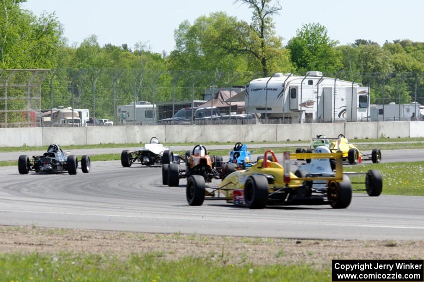 Formula cars stream through the carousel on the pace lap.