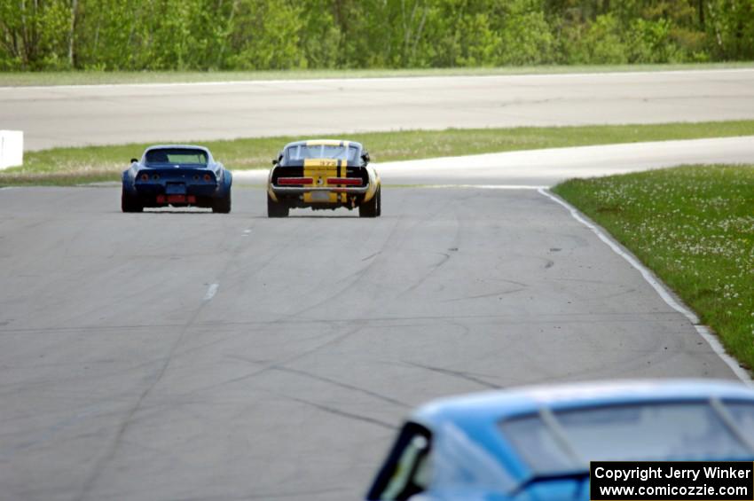 Darwin Bosell's Chevy Corvette and Shannon Ivey's Ford Mustang Shelby GT350 go side-by-side into turn one.