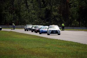 The field follows the pace car out of turn 3 under the yellow flag.