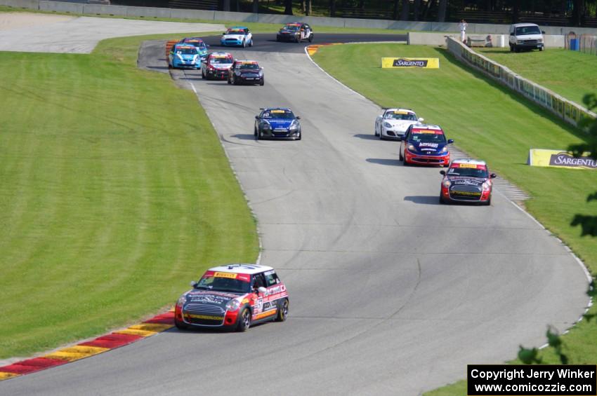 Andrei Kisel's MINI Cooper leads the field through the Hurry Downs on lap one.