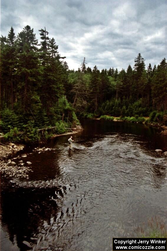 A fly fisherman at a river in the Parmachenee Forest in unaffected by the rally cars.