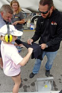 Adam Andretti signs a t-shirt for a fan.