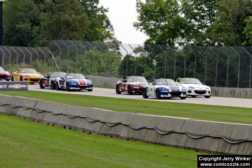 MX-5s head downhill into turn 3 on the first lap.