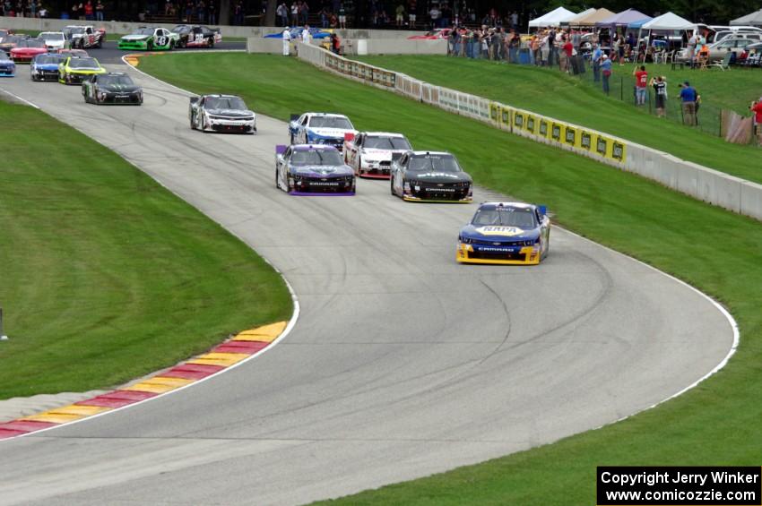 Chase Elliots's Chevy Camaro leads the field through the Hurry Downs on the first lap.