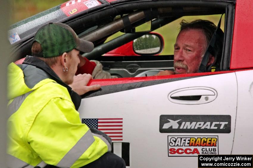 Darrell Peterson sits in his SPO Chevy Corvette while chatting with Will Cammack.