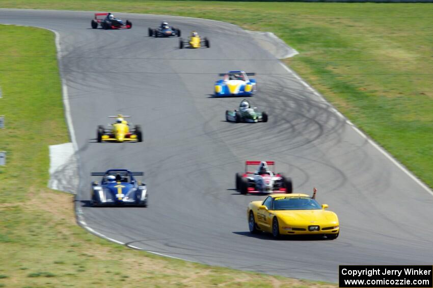 The formula car field streams into turn six on the pace lap.
