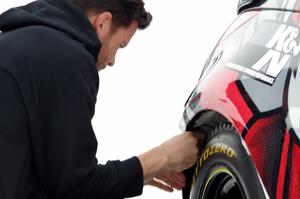 Josh Robinson makes ziptie repairs to the bumper of his Nissan 350Z.