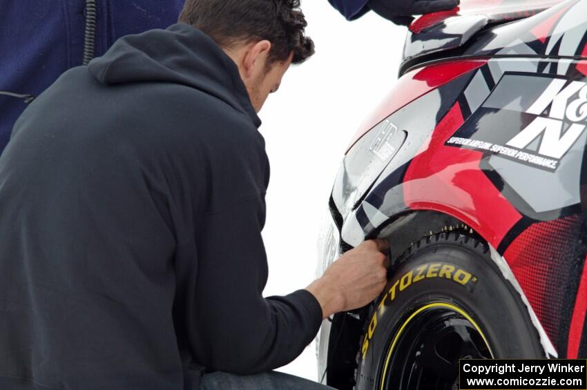 Josh Robinson makes ziptie repairs to the bumper of his Nissan 350Z.