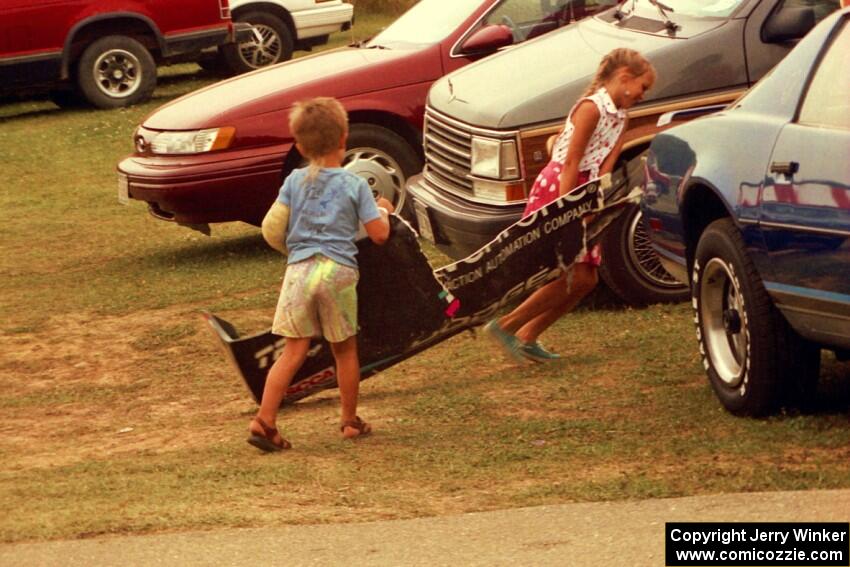 Kids bringing home parts of a Shelby Can-Am car after the race.