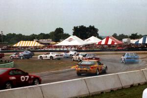 Keith Mitchell's Saturn SC and Robin Bunett's Ford Mustang lead a gaggle of cars through turn 5 at the start.