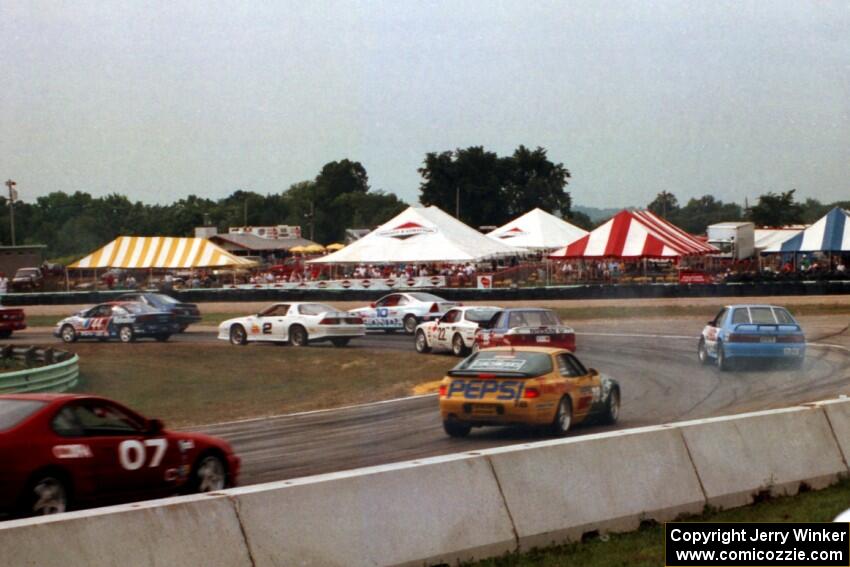 Keith Mitchell's Saturn SC and Robin Bunett's Ford Mustang lead a gaggle of cars through turn 5 at the start.