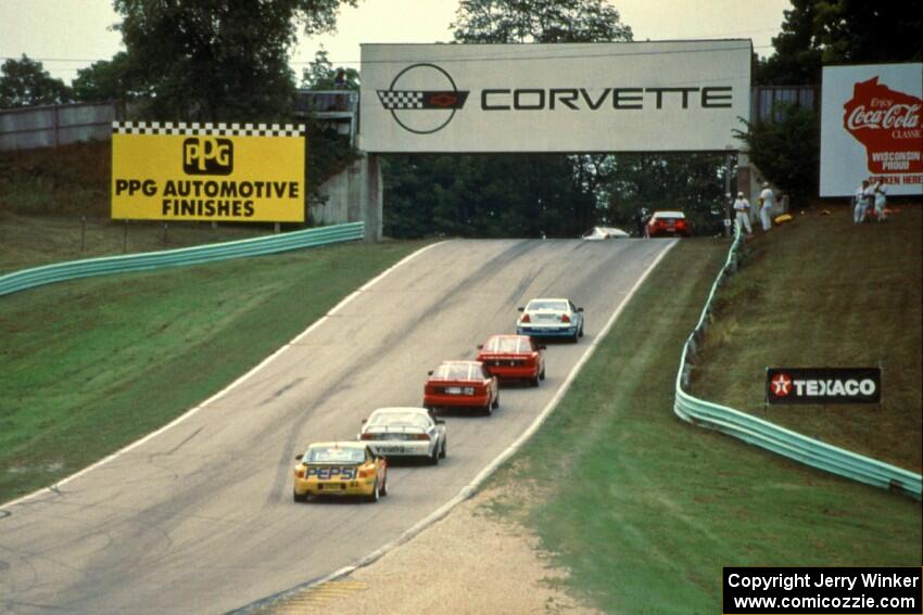 Five cars stream uphill into turn 6.