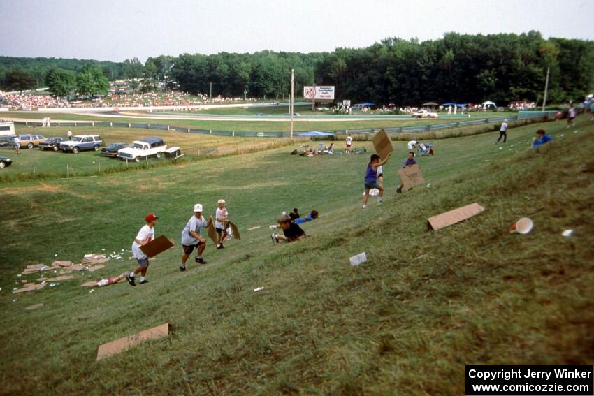 A group of kids try "sledding" down Fireman's Hill on sheets of waxed cardboard.