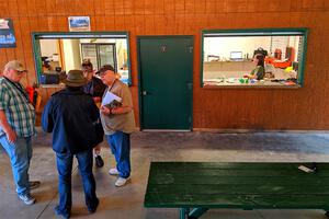 Several workers chat under the eves of the campground registration area prior to the start of the rally.