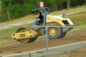 A steamroller smooths out the track surface.