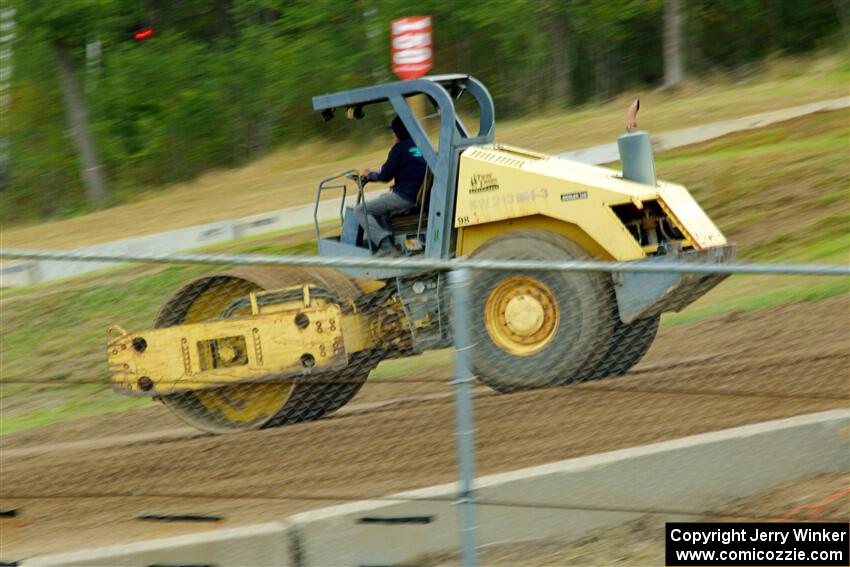 A steamroller smooths out the track surface.