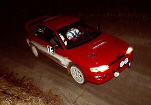 Piotr Wiktorczyk / Ray Summers at speed at night in their Subaru Impreza.