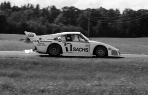 John Fitzpatrick's Porsche 935 spurts flames coming into turn four.