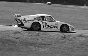 John Fitzpatrick's Porsche 935 shoots flames coming into turn four.