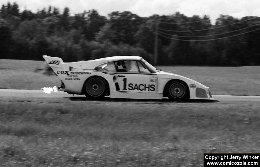 John Fitzpatrick's Porsche 935 spurts flames coming into turn four.