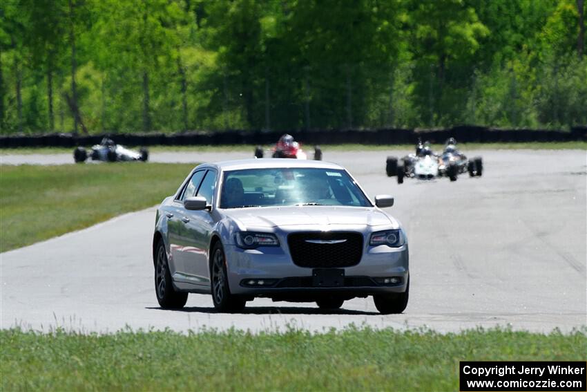 A Chrysler 300 paces the vintage formula car field.