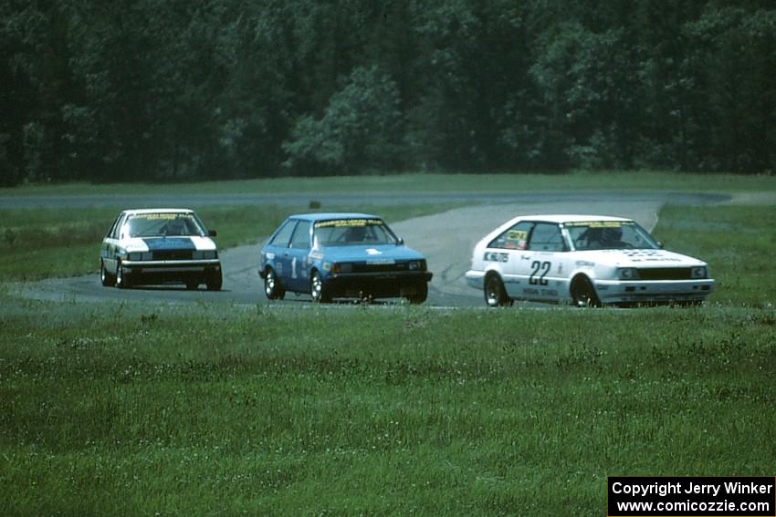 Joe Nonnamaker's Nissan Stanza leads Chuck Ulinski's Mazda 323 and Doug Peterson's Renault Alliance through turn 4.