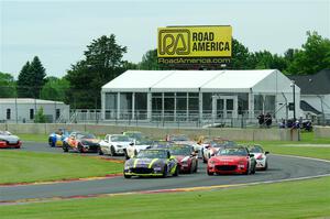 The field of Mazda MX-5 Cup cars fronted by Selin Rollan and Gresham Wagner head through turn 14 on the pace lap.