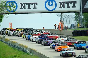 The field of Mazda MX-5 Cup cars head uphill to the green flag.