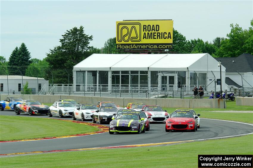 The field of Mazda MX-5 Cup cars fronted by Selin Rollan and Gresham Wagner head through turn 14 on the pace lap.