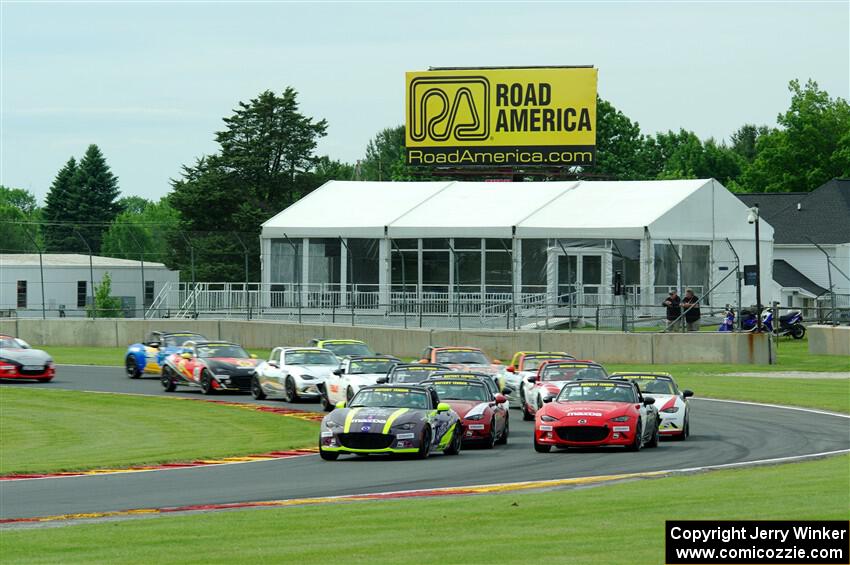 The field of Mazda MX-5 Cup cars fronted by Selin Rollan and Gresham Wagner head through turn 14 on the pace lap.