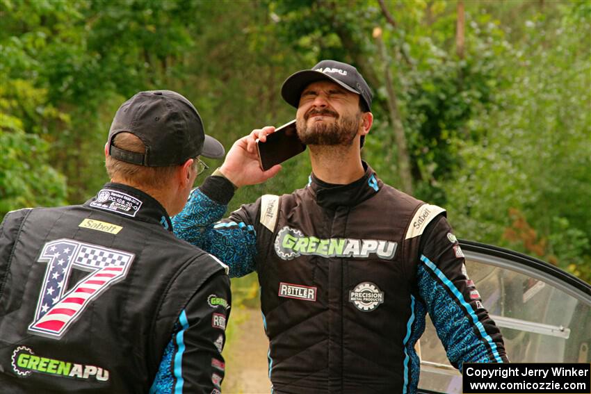 John Hall sprays insect repellant on Patrick Gruszka after their Hyundai i20 R5 stalled on SS11, Otterkill I.
