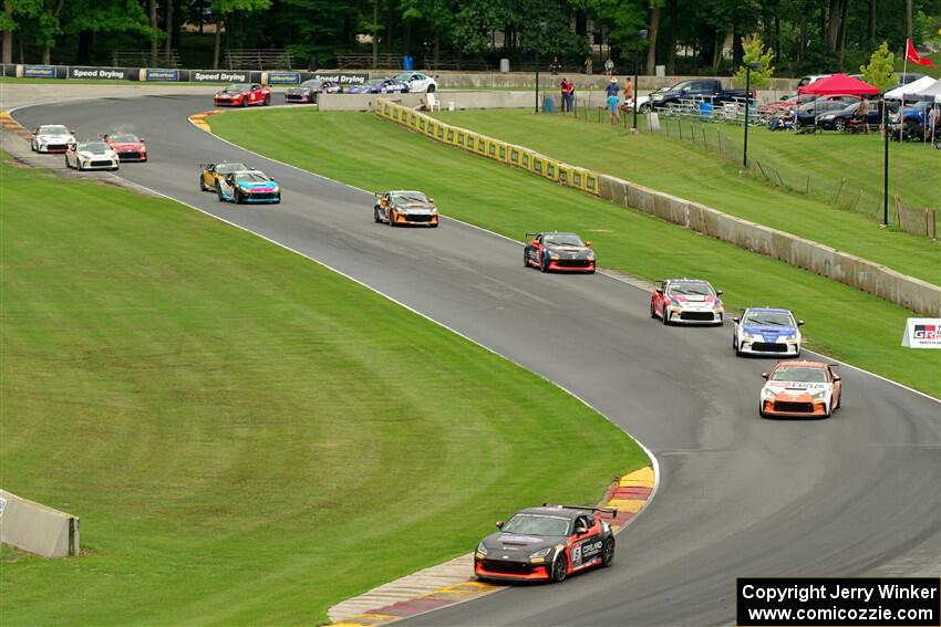 The field of Toyota GR86s streams through the Hurry Downs on lap 1 of race 1.
