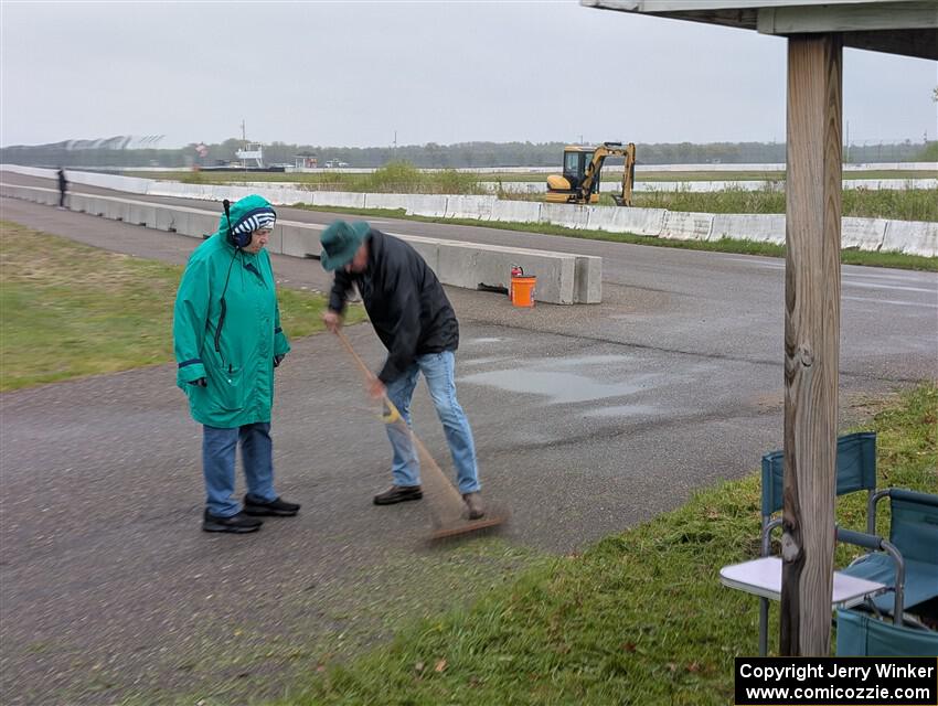 The false grid team sweeps grass up off the turn onto pit lane.