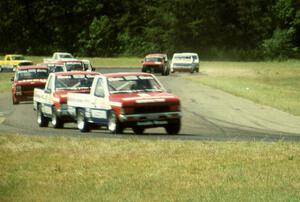 Ray Kong's and Jeff Krosnoff's Nissan Pickups lead the field through turn four.