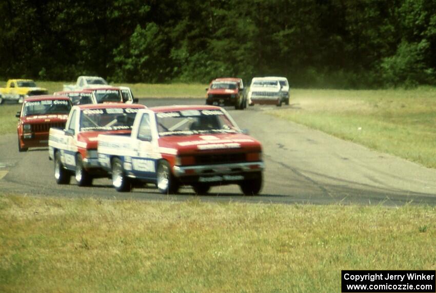 Ray Kong's and Jeff Krosnoff's Nissan Pickups lead the field through turn four.