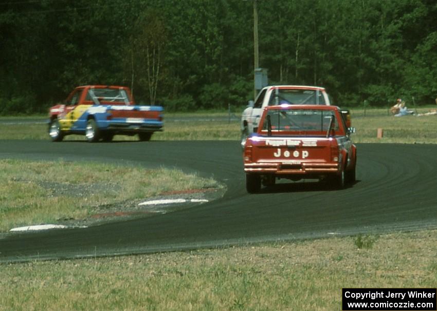 Tom Nields' Dodge Ram D-50 leads Chuck Hemmingson's Jeep Comanche and Larry Nuber's Jeep Comanche through turn 4.