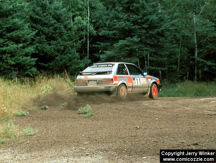 Jeff Zwart / Cal Coatsworth in their Mazda 323GTX hit the gas at the exit of a hairpin.