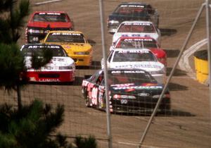 Eight cars, led by Dick Trickle, stream out of corner 4