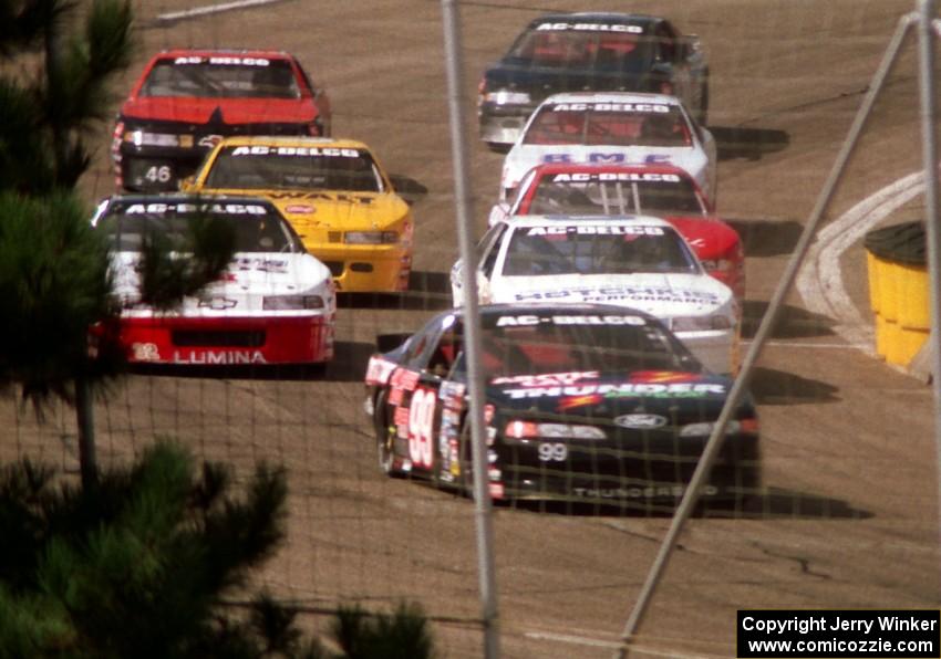 Eight cars, led by Dick Trickle, stream out of corner 4
